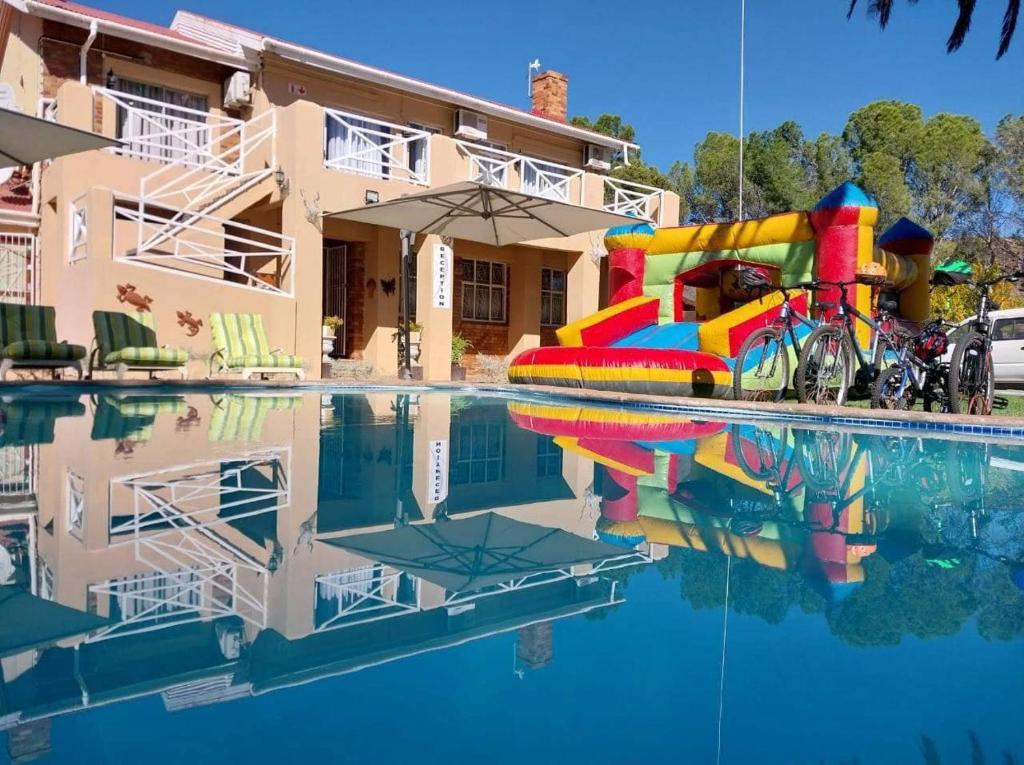 einem Pool mit einer Wasserrutsche vor einem Gebäude in der Unterkunft Victoria Oaks Guesthouse in Victoria West
