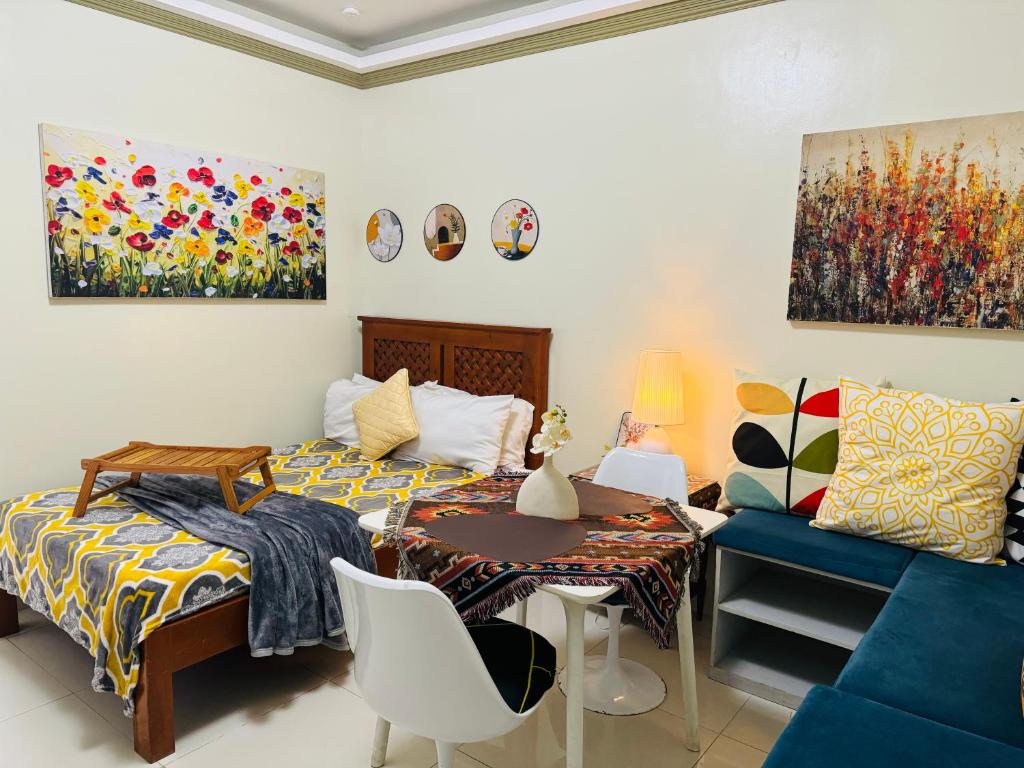 a bedroom with a bed and a table and a couch at PREMIUM CONDO AT BRENTHILL BAGUIO in Baguio