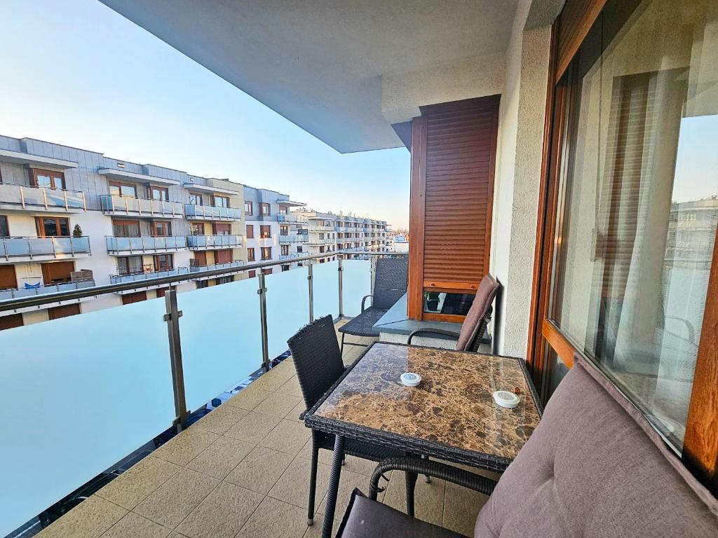 a balcony with a table and chairs and a view of the water at Piernikowy Apartament 52 in Toruń