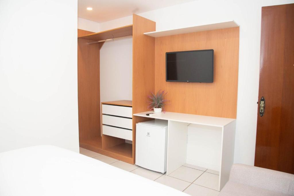 a room with a tv on a wall with a desk at POUSADA PEDRA DE JACÓ in Lauro de Freitas