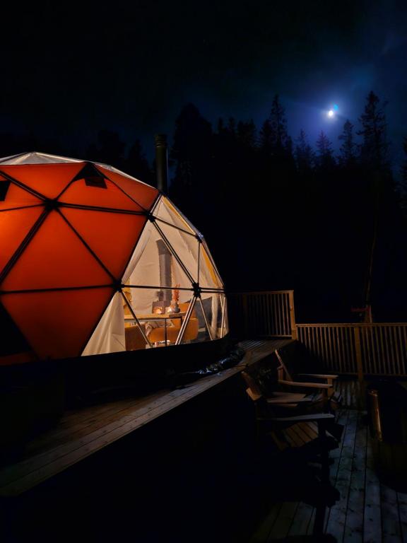 a large red and white tent on a deck at night at Forbord Dome 