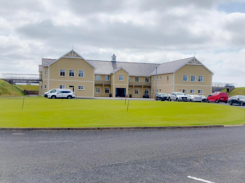 un grand bâtiment avec des voitures garées devant lui dans l'établissement Mews Apartment Main St, Carrigart, F92HC04, à Carrigart