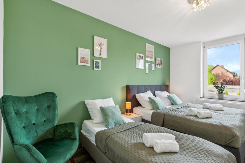 a bedroom with two beds and a chair and a window at Elegant & Bright ~ Near Schalke 04 ~ Office ~ Free Parking! in Gelsenkirchen