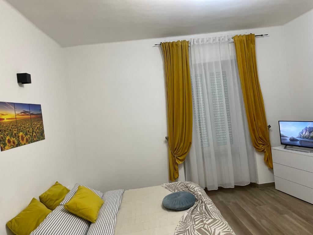 Schlafzimmer mit einem Bett mit gelben Vorhängen und einem TV in der Unterkunft Savonarola Almarc 2 in Alessandria