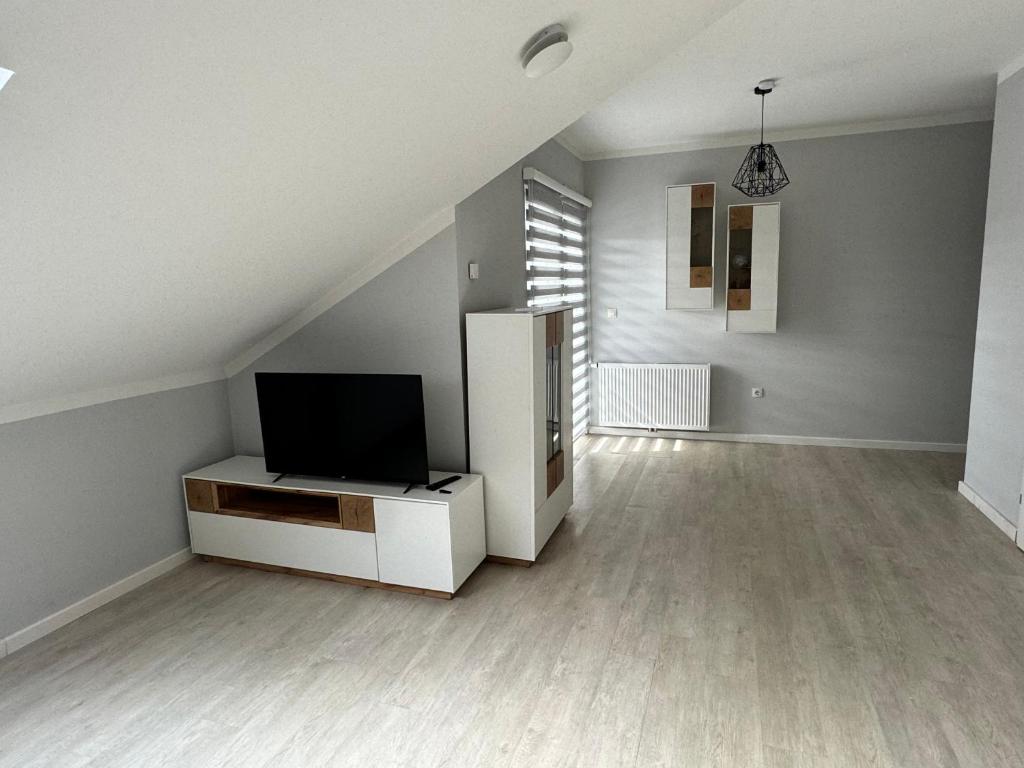 - un salon avec une télévision et un réfrigérateur blanc dans l'établissement XL Apartman, à Teslić