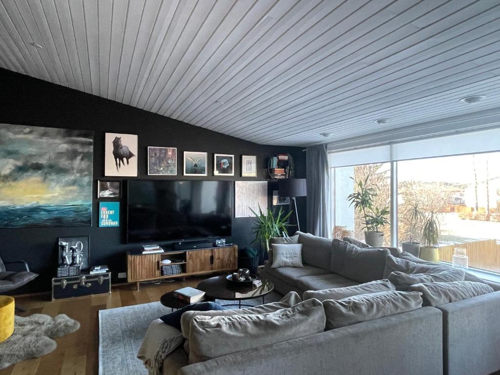 een woonkamer met een bank en een flatscreen-tv bij Spacious & luxurious family home w hot & cold tub & sauna in Reykjavík