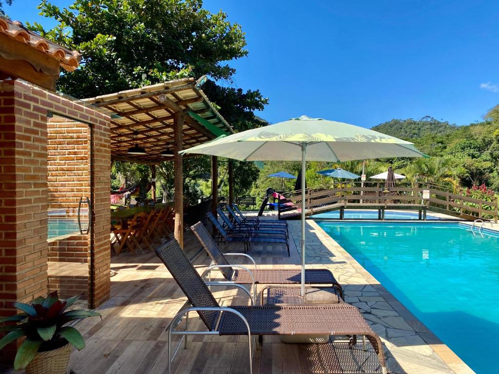 a patio with chairs and an umbrella next to a pool at Estação Serramar in Lumiar