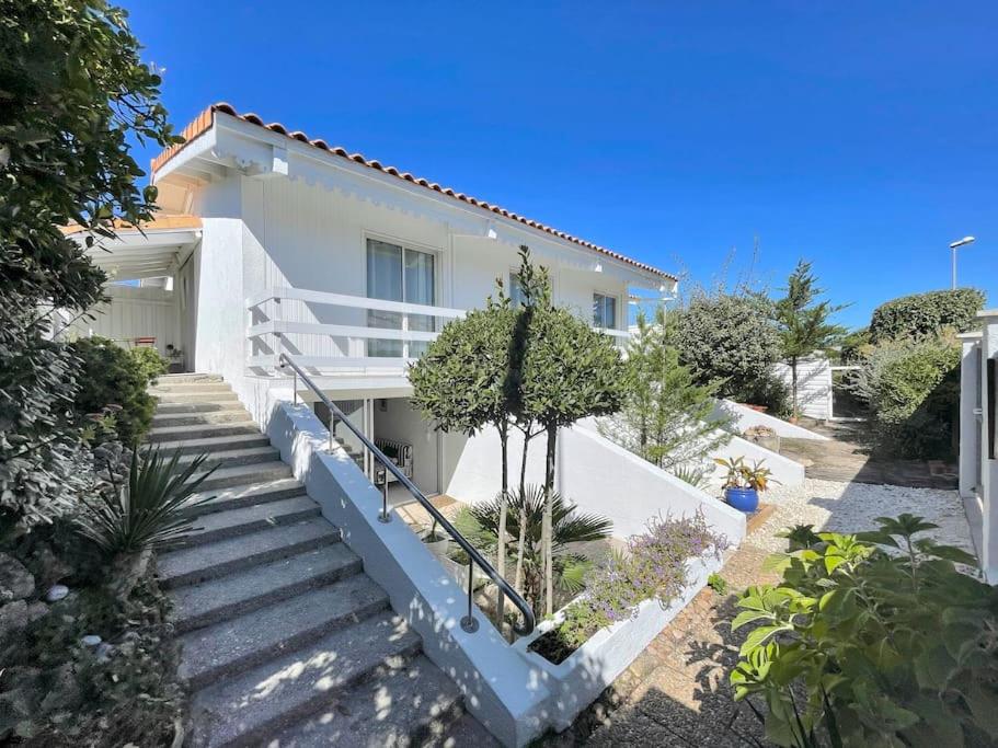 une maison blanche avec des escaliers en face de celle-ci dans l'établissement Villa vue direct océan 21 couchages, à Hourtin