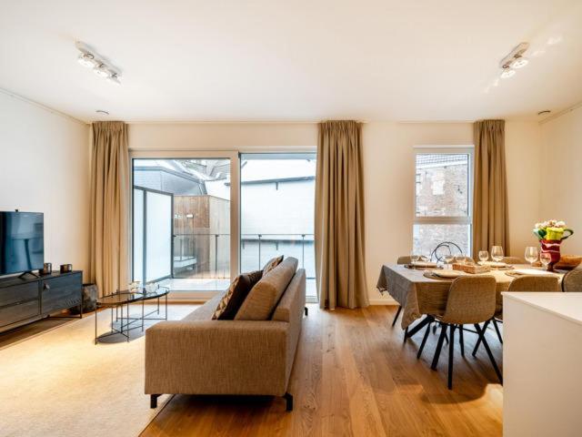 sala de estar con sofá y mesa de comedor en Jolie appartement haut standing Liège Guillemins en Lieja