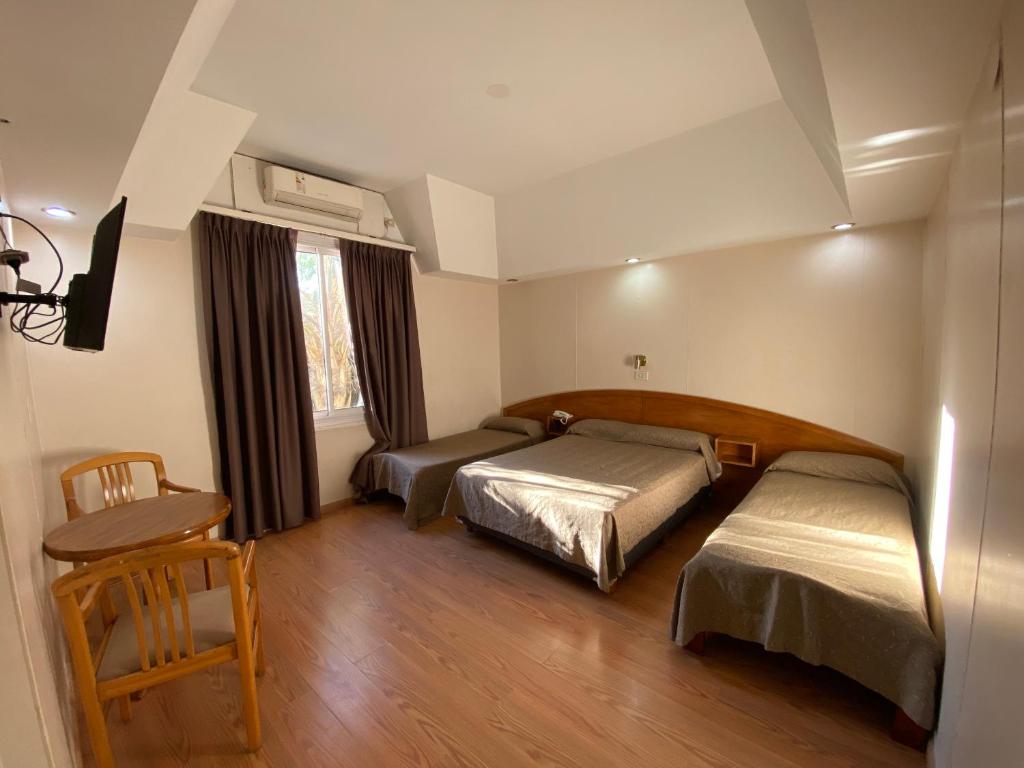 1 dormitorio con 2 camas, mesa y silla en HOTEL PALERMO BUENOS AIRES en Buenos Aires