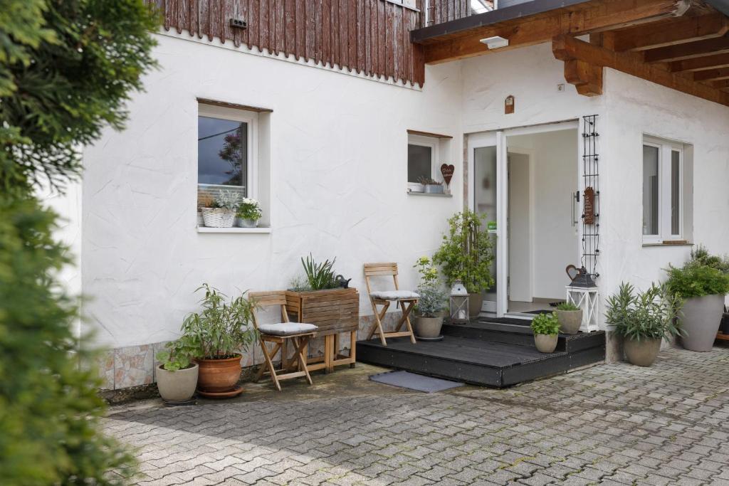 a white house with potted plants on a patio at Ferienwohnung Mittenglück in Unterlenningen