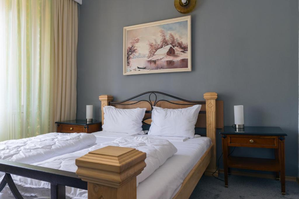 a bedroom with a bed with two night stands and two tables at Vila Pufu in Slănic-Moldova