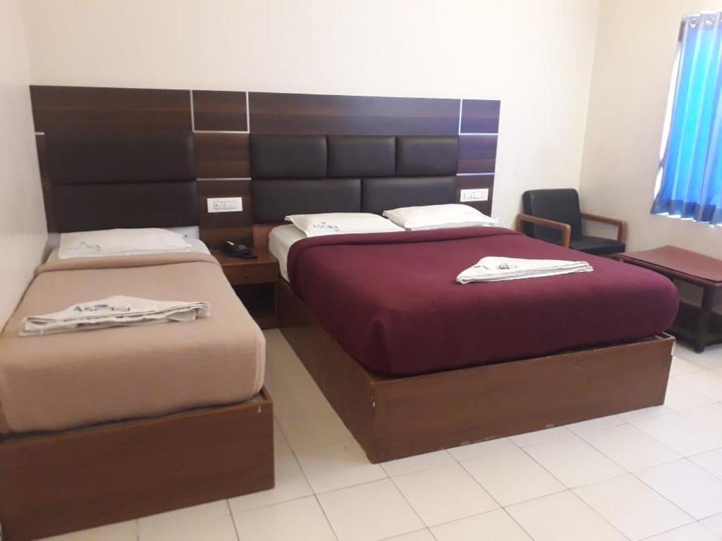 Dos camas en una habitación de hotel con toallas. en Asokainn, en Mettuppālaiyam