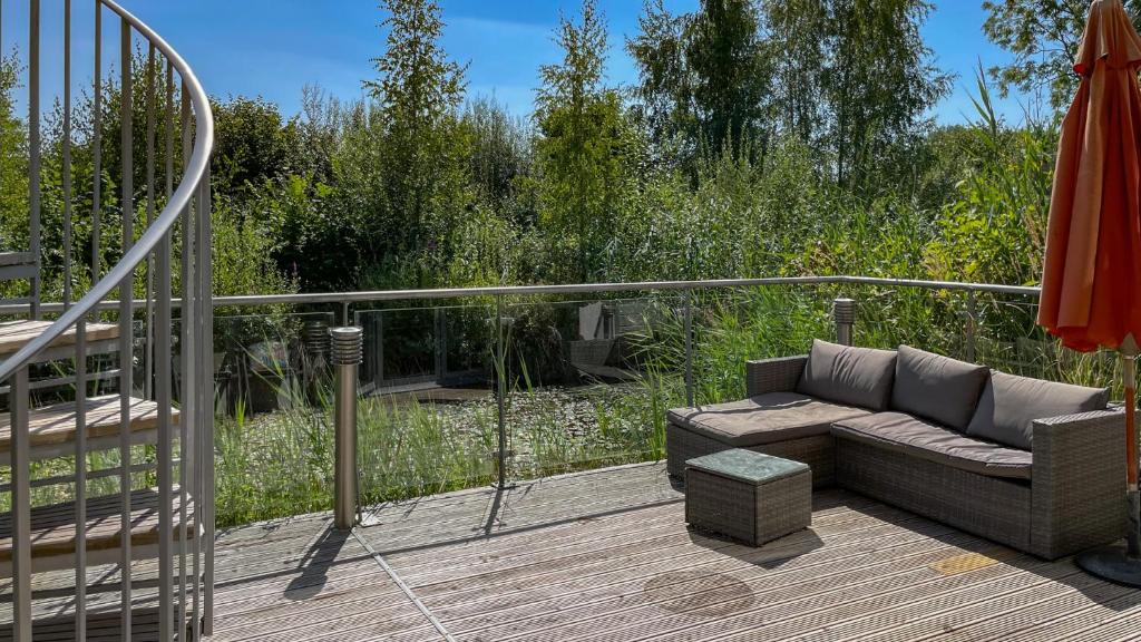 a patio with a couch and an umbrella on a deck at Muntjac Lodge in Somerford Keynes