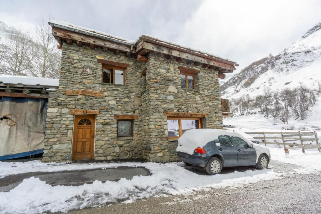 a car parked in front of a stone house in the snow at Chalet Les moulins in Bonneval-sur-Arc