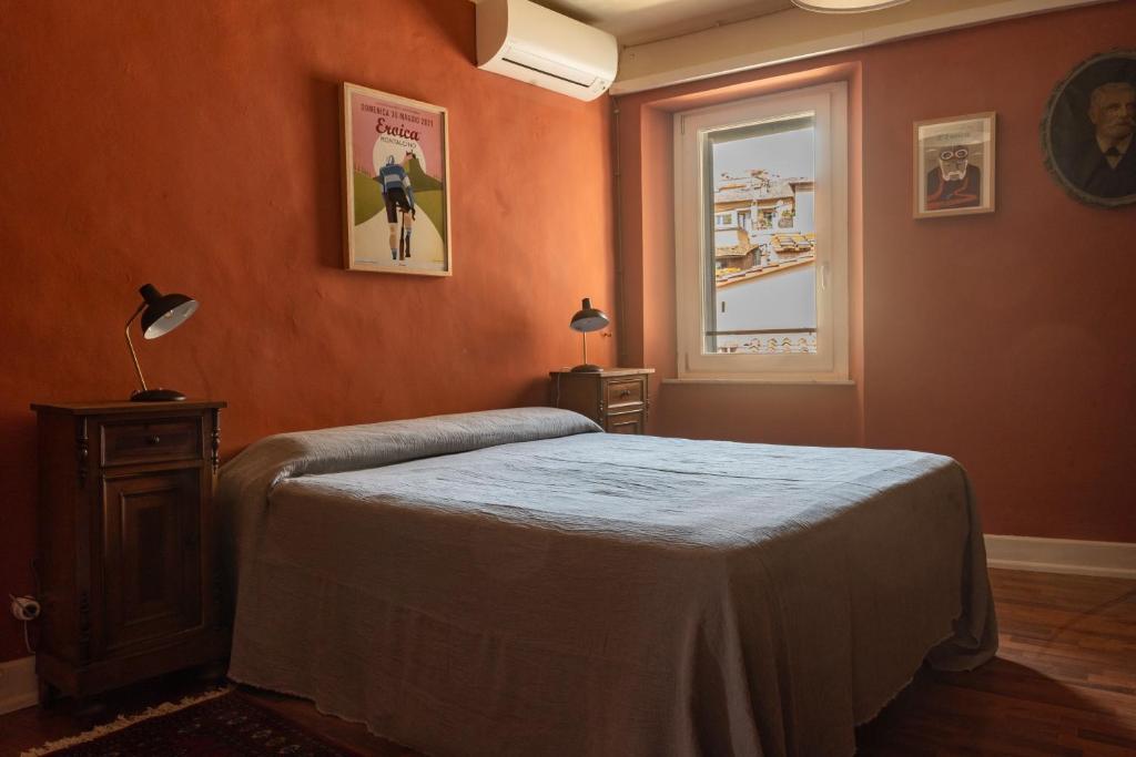 een slaapkamer met oranje muren en een bed en een raam bij BirBo Bike Hospitality in Siena