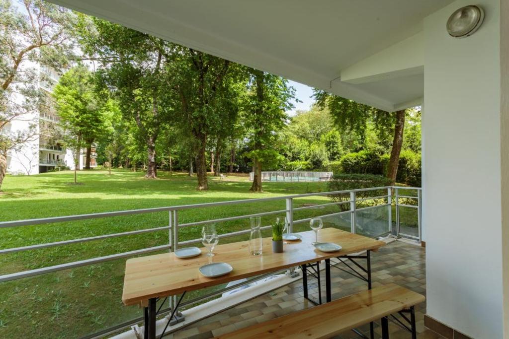 a table on a balcony with a view of a park at Appartement d'exception proche des commerces avec piscine in Biarritz