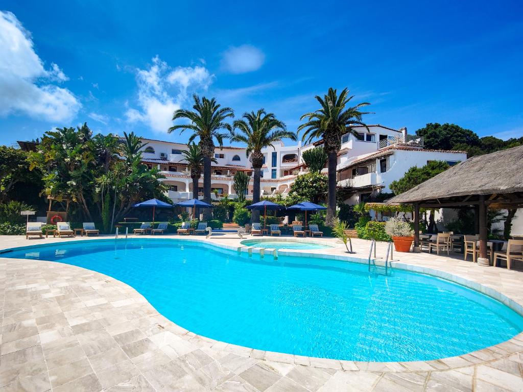 uma piscina num resort com palmeiras em Hotel Balocco em Porto Cervo