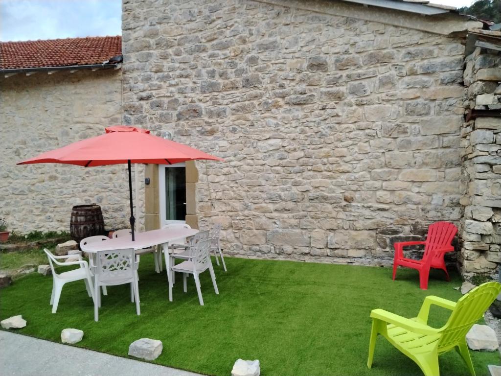 a patio with a table and chairs and an umbrella at Maison de Fernand in Montjay