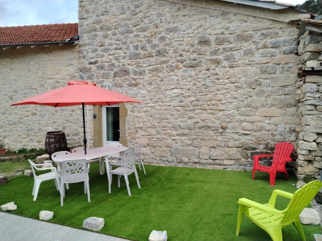un patio avec une table, des chaises et un parasol dans l'établissement Maison de Fernand, à Montjay