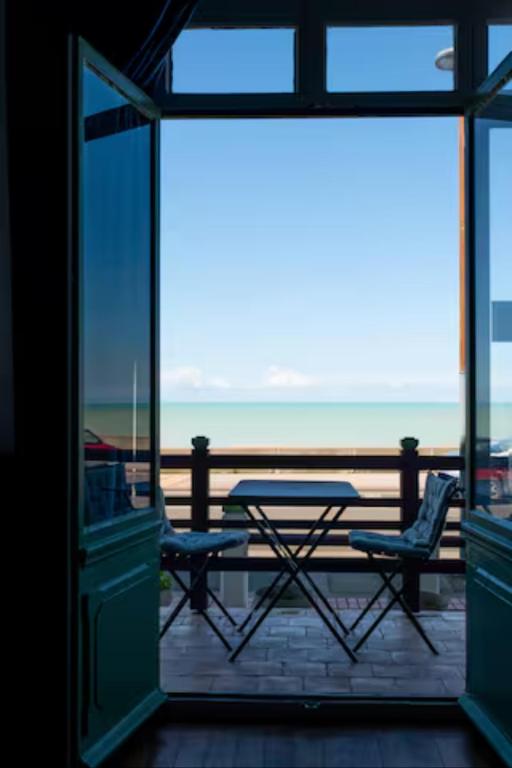 une vue d'un balcon avec une table et des chaises dans l'établissement La Découverte, appartement front de mer Mers, à Mers-les-Bains