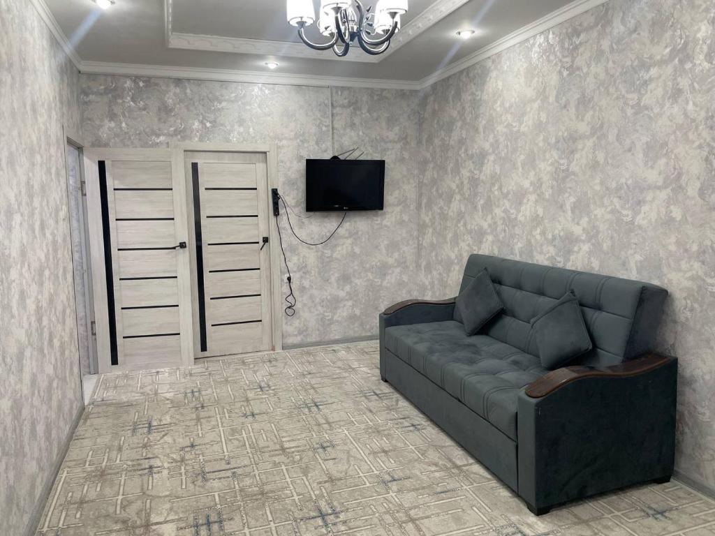 sala de estar con sofá y TV en la pared en Yunusabad 15, Tashkent, en Tashkent