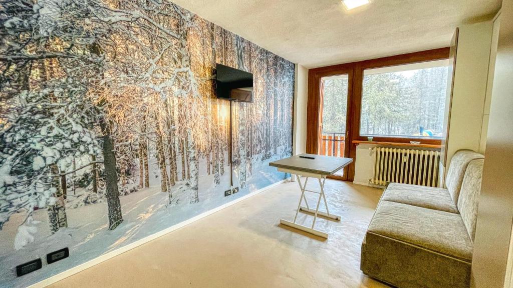 ein Wohnzimmer mit einem Wandbild von Bäumen in der Unterkunft Appartamento Dolmaire - Affitti Brevi Italia in Sauze dʼOulx