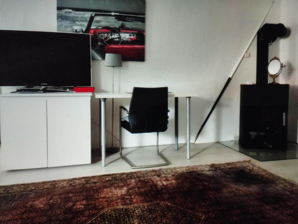 a living room with a desk with a tv and a chair at Ferienwohnung in Thermalbadnähe in Bad Saulgau