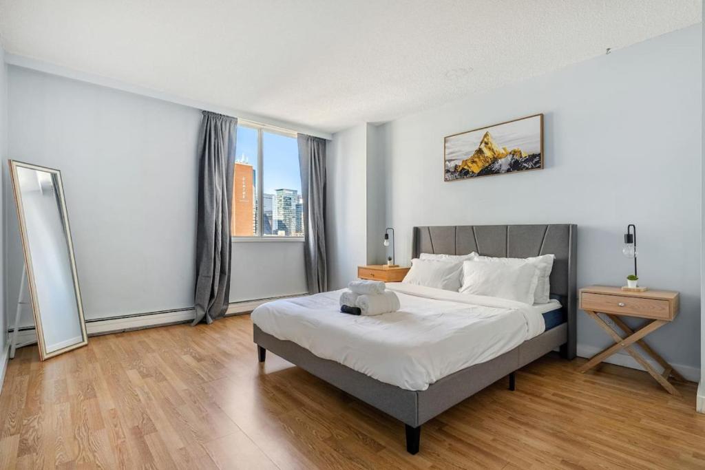 a bedroom with a bed and a large window at Only 5 minutes to Rogers with Downtown Views in Edmonton