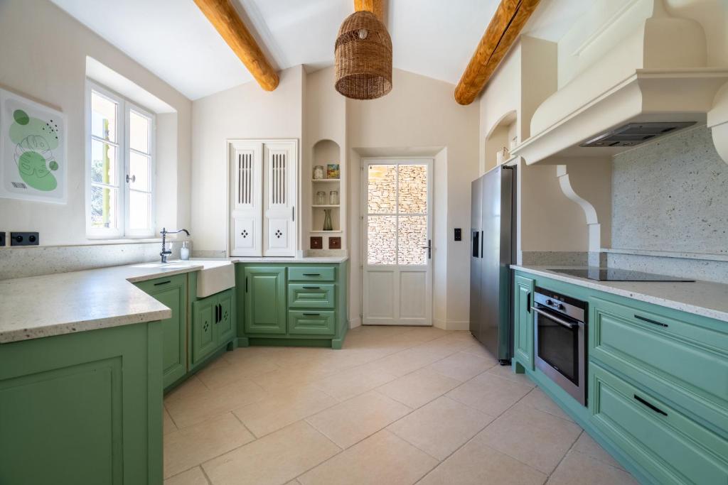 a kitchen with green cabinets and a sink at La Bastide Des As in Gordes