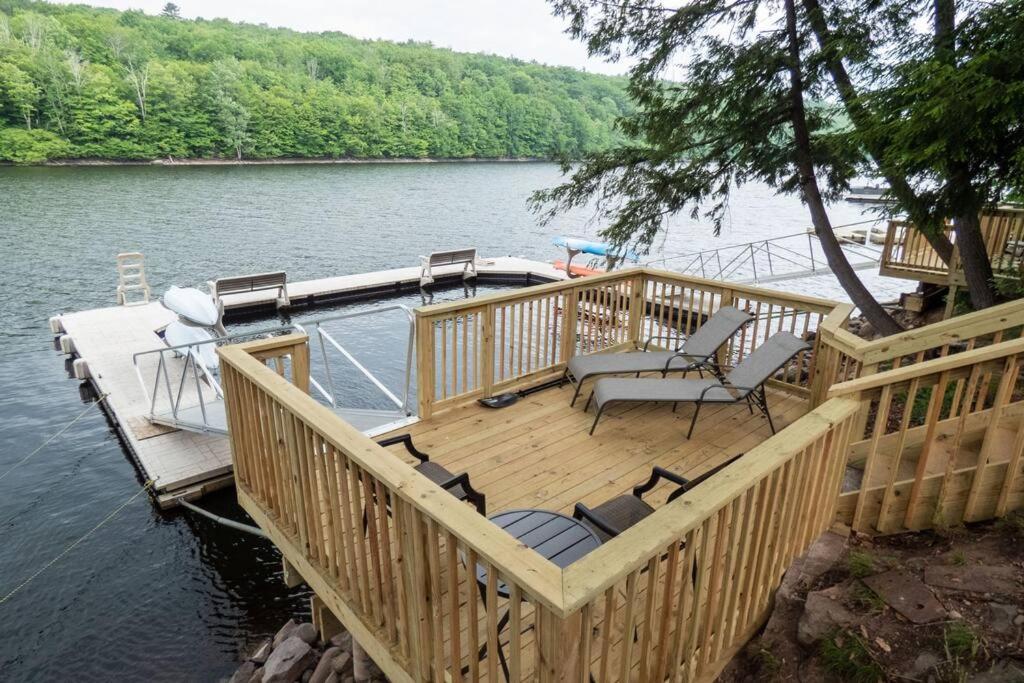 eine Holzterrasse mit Stühlen und einem Boot auf dem Wasser in der Unterkunft Lakefront Haven Home in Monticello