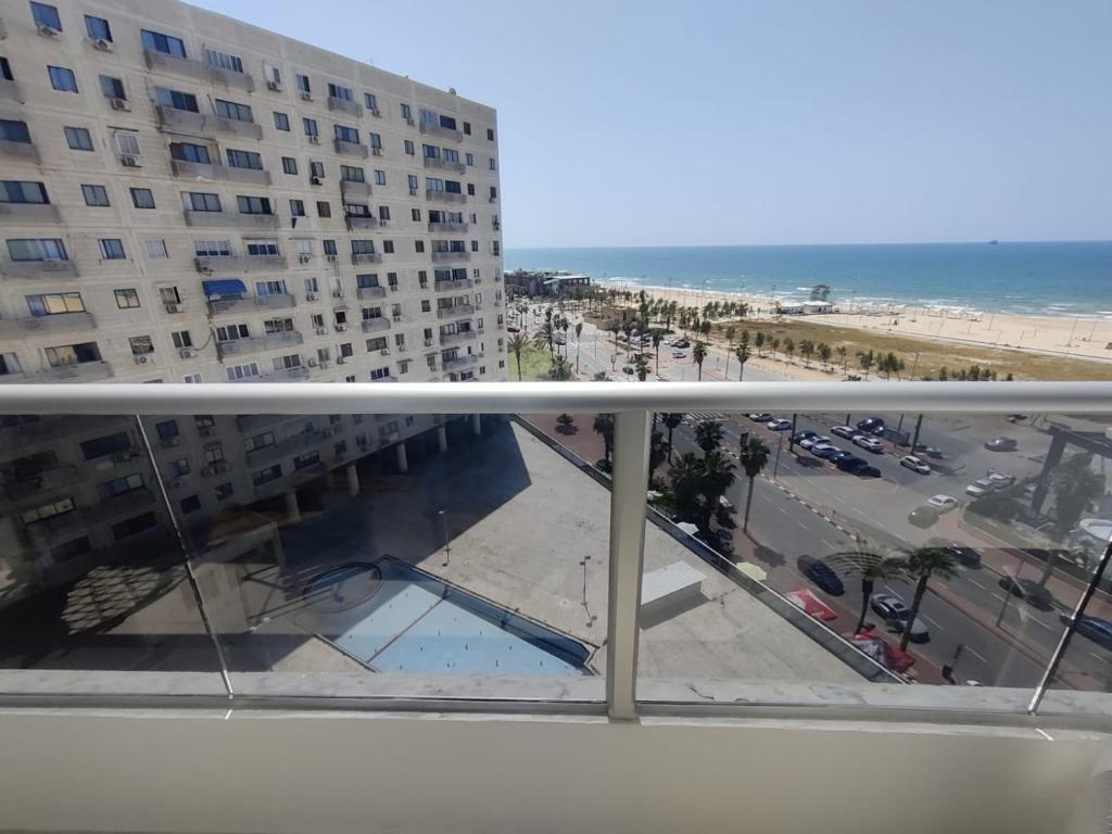 balkon z widokiem na plażę i budynek w obiekcie סוויטת פאר מול הים w mieście Aszdod