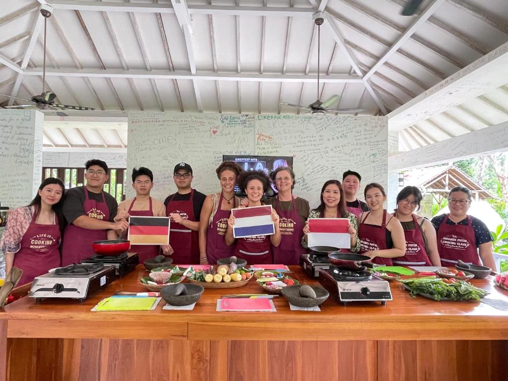 Anggrek Putih Homestay & Cooking Class في سينغيغي: مجموعة من الناس تقف حول طاولة مع الطعام