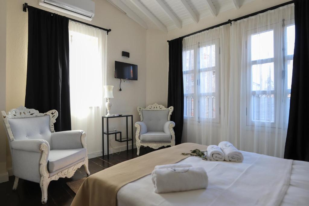 a bedroom with two chairs and a bed with towels at Lilla Maria Guesthouse in Ayvalık