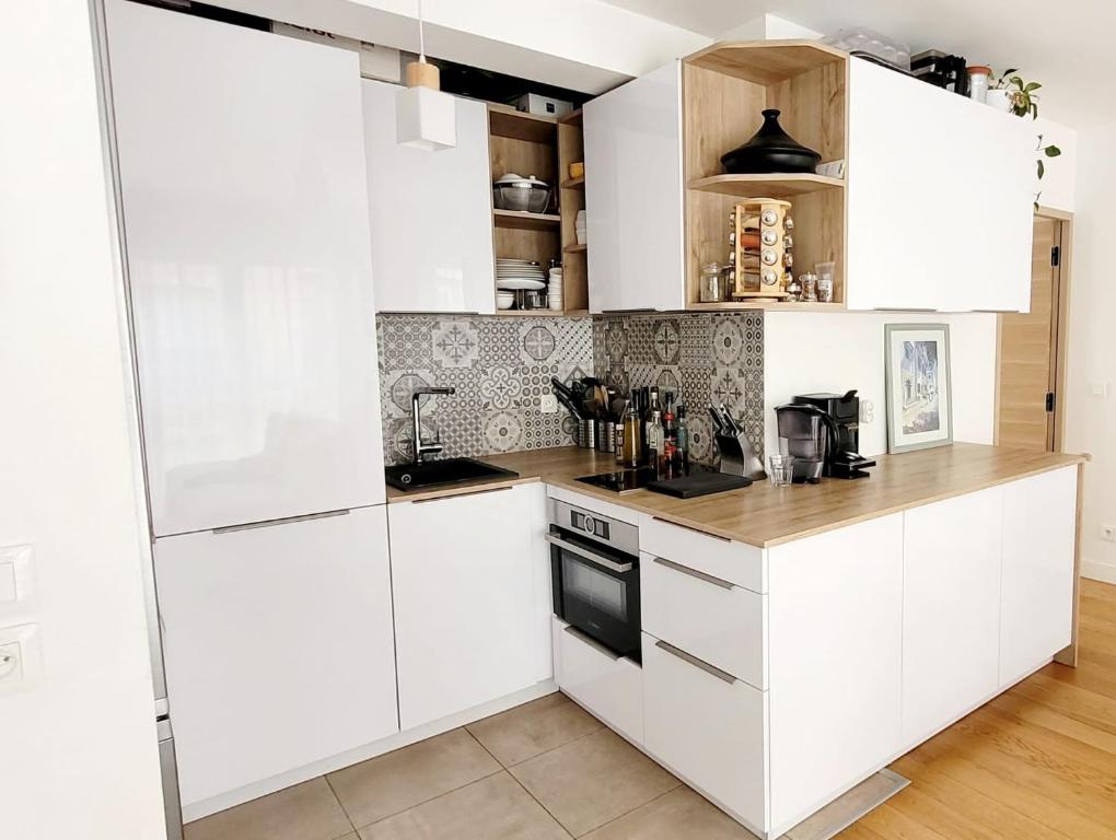 cocina con armarios blancos y encimera en Chic & Cosy apartment - 60m2, 3 rooms, en Asnières-sur-Seine