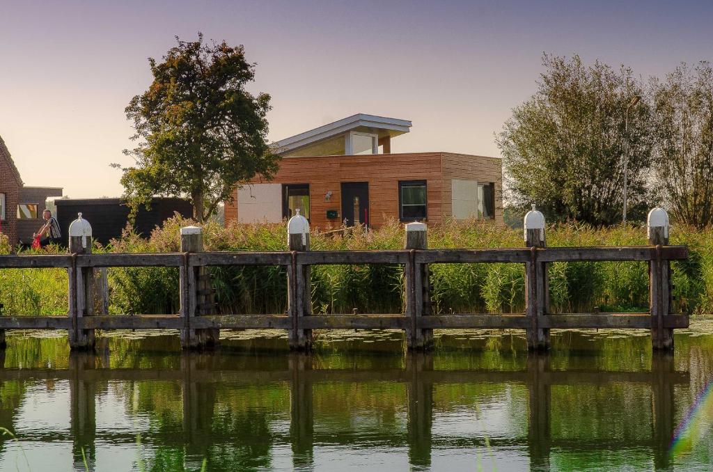 una casa junto al agua con un puente en Aan de Amstel, en De Kwakel