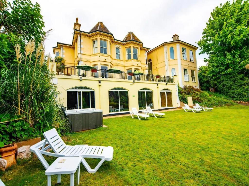 a large yellow house with white chairs in the yard at Crofton House Hotel in Torquay
