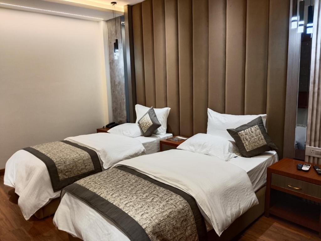 una camera d'albergo con due letti con lenzuola bianche di Western Blu INN a Nuova Delhi