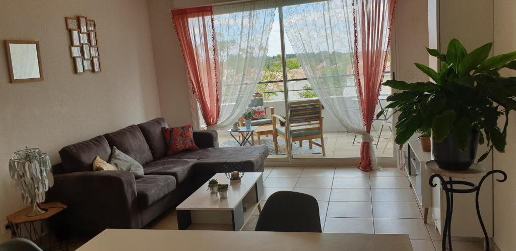 uma sala de estar com um sofá e uma mesa em Appartement T2 à 10 min de Montpellier em Vendargues