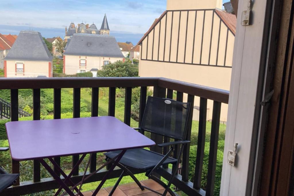 een tafel en een stoel op een balkon met uitzicht bij Renovated apartment - near the beach in Ouistreham