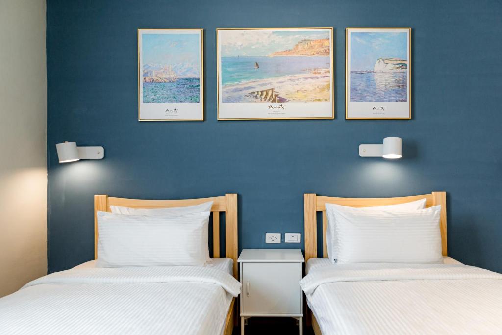 2 camas en una habitación con 3 cuadros en la pared en Water World Diving Resort, en Isla Verde