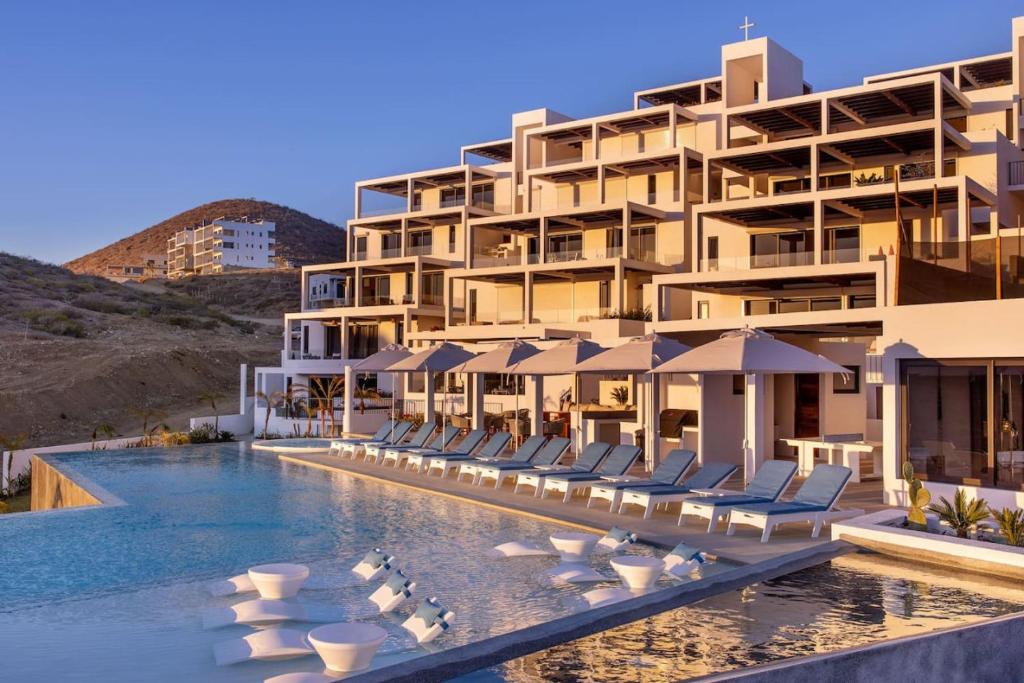 un hotel con una piscina con sillas y sombrillas en Beachfront Retreat in Cerritos, en El Pescadero