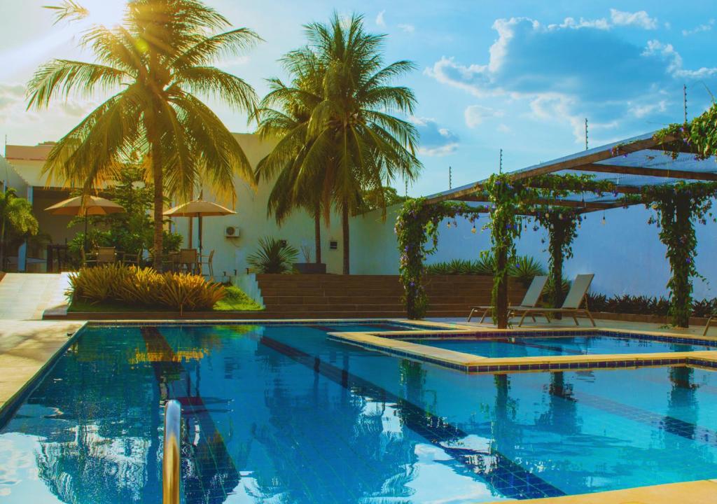 a swimming pool with palm trees in a resort at Nord Luxxor Juazeiro do Norte in Juazeiro do Norte