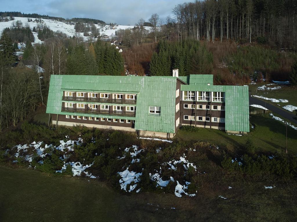 un bâtiment avec un toit vert au-dessus d'un champ dans l'établissement Hotel Albert, à Paseky nad Jizerou