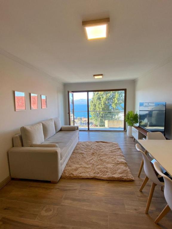 ein Wohnzimmer mit einem Sofa, einem Tisch und einem TV in der Unterkunft Departamento en el Corazon de Bariloche in San Carlos de Bariloche