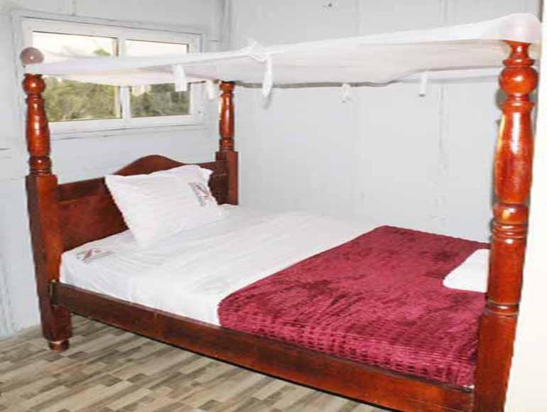 um quarto com uma cama de dossel e um cobertor vermelho em Loginecoresort em Lukunyu