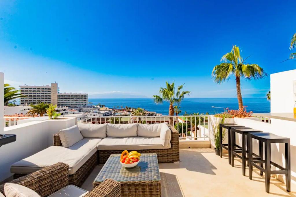 eine Terrasse mit einem Sofa, Tischen und Meerblick in der Unterkunft 2 Bedroom Apartment - Terrace & Sea View - Los Gigantes in Acantilado de los Gigantes