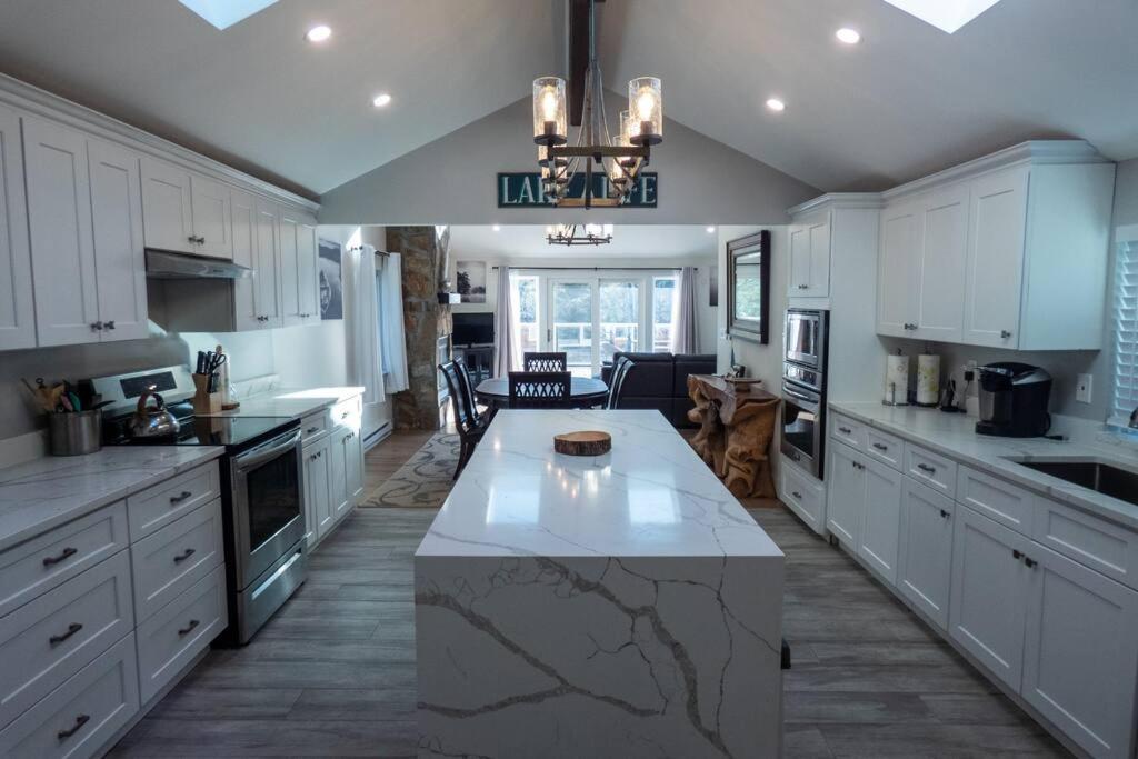 a large kitchen with white cabinets and a marble island at Sun Drenched Lakefront Cove in Monticello