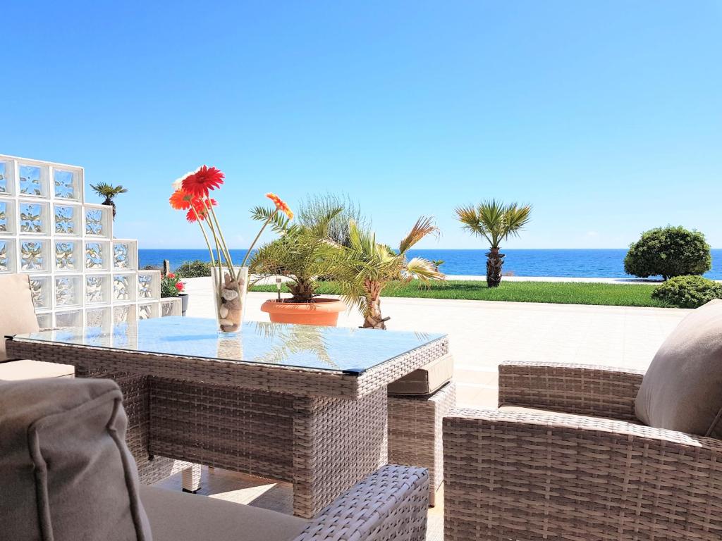 a patio with a table and chairs and the ocean at Villa Alexandros in Alexandroupoli