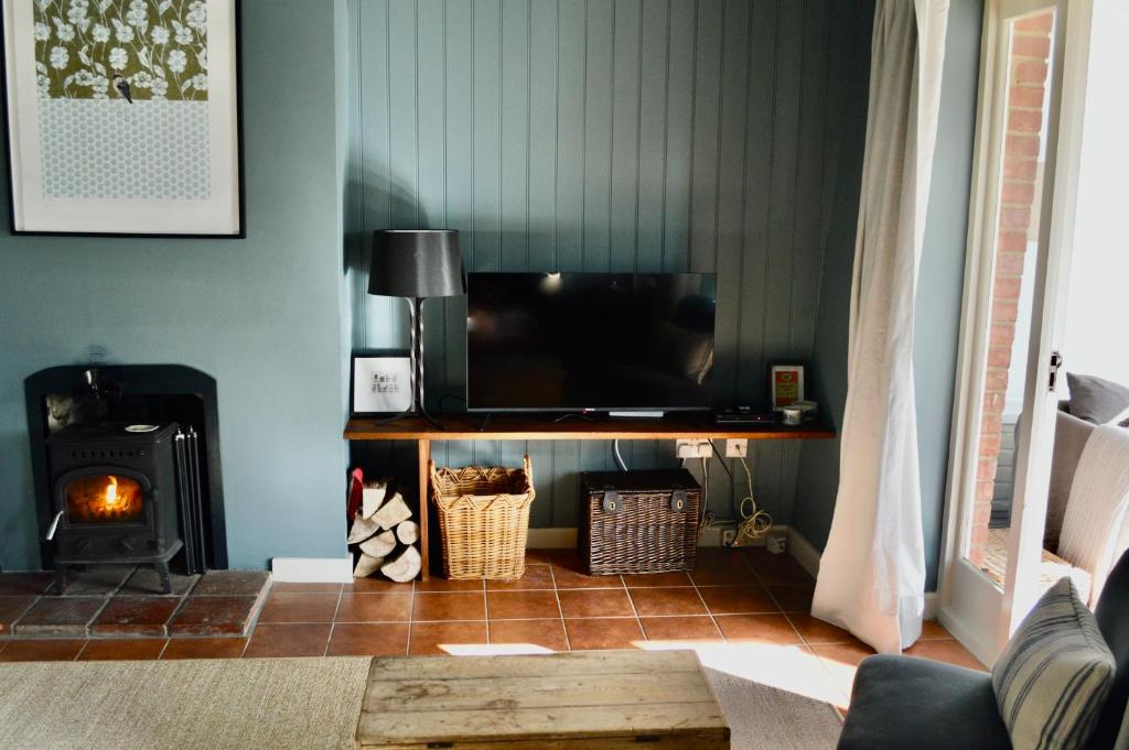 a living room with a television and a fireplace at Gryngolet Cottage - with Artist Studio - Crabpot Cottages Sheringham in Aylmerton